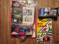 Top view of the lot showing the 2001 Chipper Jones card and Atlanta Braves PT Cruiser in original packaging, the Terry Labonte #5 Kellogg's Corn Flakes keychain in yellow packaging, and the boxed Michael Waltrip Racing Best Western Toyota Camry #00 diecast car.