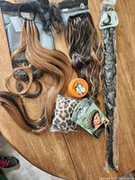 Photo of multiple hairpieces, satin bonnets, a jar of Murray's Hair Dressing, and hair accessories on a wooden table.
