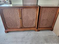 Front view of the wooden Hoffman stereo cabinet and separate satellite speaker with fabric-covered fronts