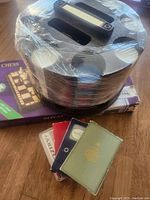 Poker chip spinner wrapped in plastic on top of wooden chess set box, four decks of cards in front.
