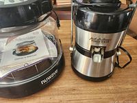 Photo of Jack LaLanne Power Juicer Express showing stainless steel body, black top, power cord and operator manual.