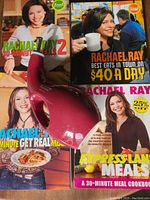 Four Rachael Ray cookbooks arranged with a red bottle on top, showing book titles and covers clearly.