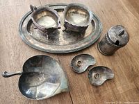 Photo showing an oval tray with two candleholders, a lidded container, a leaf-shaped small dish, two kidney-shaped bowls, and two small heart-shaped plates.