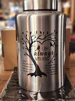 Photo of stainless steel urn with tree and bird design, text inscribed 'I am always with you'