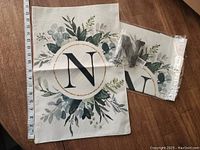 Two fabric yard flags each 12 x 18 inches, white with green botanical wreath around letter 'N', plus one small wooden letter 'N' with mounting hardware