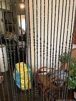 Full view of the black twisted beaded doorway curtain hanging in a room showing overall size and design.