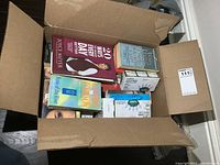 Open cardboard box showing multiple books stacked inside along with some boxed items