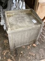 Front and top view of the small resin Suncast deck box seat showing wear and dirt accumulation on the surface and sides.