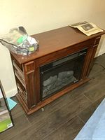 Front view of electric fireplace with manual and spare motor on top.