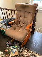 Front angle view of the brown cushioned vintage glider rocker chair showing the seat, armrests and base