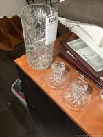 Clear image showing tall crystal vase and pair of crystal candle holders on wooden surface.