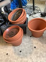 Multiple clay planters stacked showing use inside, one clay planter upright on floor