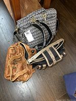 Three handbags including new black and white patterned backpack style purse with tags, brown leather handbag, and black purse with beige straps