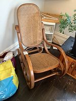 Front angled view of bentwood rocking chair showing cane seat and backrest with curved wood frame
