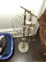 Full view of the chrome shoe rack standing on floor next to a plastic bin and a brown stuffed item.