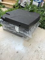 Set of 4 stacked new black umbrella weights with textured surface and filling hole visible.