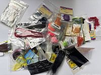 Overview of numerous bags of new fly fishing tying flash materials, various colors and types including tinsel and marabou flash fibers.
