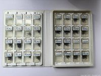 Open fly fishing hook file binder showing clear plastic compartments filled with various sizes of TMC fly fishing hooks, each compartment labeled with hook size and type.