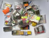 Overview of the lot showing a variety of sealed plastic bags filled with various dubbing materials and some small boxes of dubbing colors.