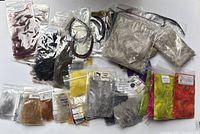 Collection of multiple sealed bags containing new feathers for fly tying in various natural and bright colors, showing overall lot contents.