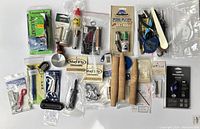 Overview photo showing all items in lot including wooden tool hangers, bobbin holders, glue, clipper, packaged Struble reel seat, and other fly fishing tying tools and accessories.