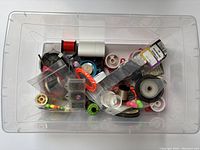 Top view of plastic case showing varied fly fishing equipment including spools, tools, and containers.