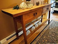 Side angled view of the wooden hall console table showing two drawers with metal handles and a thick wooden top.