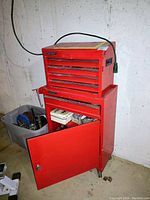 Full view of the red Storehouse metal rolling tool cabinet against basement wall with top chest and bottom cabinet open showing tools inside.