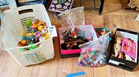 Photo showing a white plastic bin filled with brightly colored rubber ducks, two shoeboxes containing vintage matchbox cars and dolls.