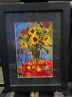 Framed floral print showing proteas, sunflowers, and lemons on a red table with bright background