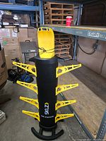 Full front view of the SKLZ electric air dryer showing the black central cylinder with yellow extendable arms and yellow top hood.