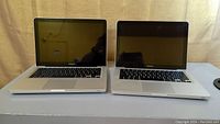 Two Apple MacBook Pro laptops, 13-inch, Model A1278, closed and open view showing front and keyboard area.