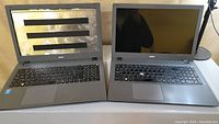 Two Acer Aspire E5 15-inch laptops side by side, one with screen removed showing internal frame, other with screen intact