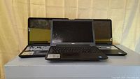 Three Dell Inspiron 15 laptops shown together, two removed keyboards and one fully assembled laptop in front