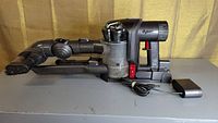 Side view of Dyson DC45 Animal vacuum with attached power adapter and three attachments, no wand included