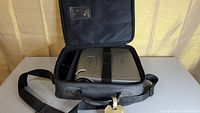 Top view of black carrying case open showing Infocus projector inside secured by black strap