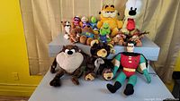 Photo showing variety of plush stuffed animals including Robin, Taz, teddy bear, moose, Garfield