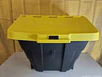 Closed black plastic storage bin with yellow hinged lid, highlighting the clip lock mechanism and stackable design.