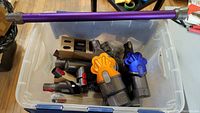 Tote containing assorted Dyson vacuum parts including two cyclone assemblies, wand, and multiple attachments