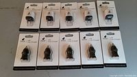Five black USB car chargers sealed in packaging, shown in one row, and five white USB wall chargers sealed in packaging, shown in another row.