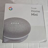 Front of sealed retail box showing Google Home Mini image and branding.
