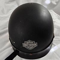 Front view of black Harley Davidson motorcycle helmet showing logo on front and minor scratches.