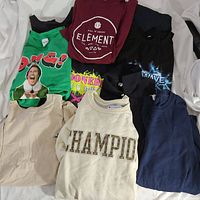 Top view of assorted men's shirts neatly folded featuring graphic designs and brand logos.