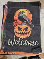 Photo showing a flag with a black crow perched on a jack-o'-lantern with 'Welcome' text.