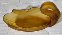 Matte amber glass swan-shaped candy dish with swan head handle, showing the open shallow dish and wing details.
