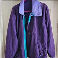 Front view of the purple Patagonia jacket hanging, showing teal inner lining and lavender collar.