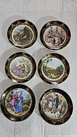 Set of six Regency style bone china plates arranged in two columns of three showing detailed scenic illustrations with black and gold ornate rims