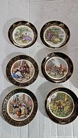 Six vintage Regency English bone china plates laid out on plain background. Plates have black rims with gold intricate pattern and detailed period scenes in center.