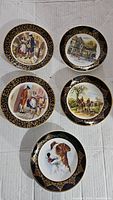 Five bone china plates arranged flat showing detailed scenes and black gold patterned borders.