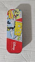 Top view of the rectangular red metal tin box decorated with Disney comics featuring Mickey Mouse and other characters.